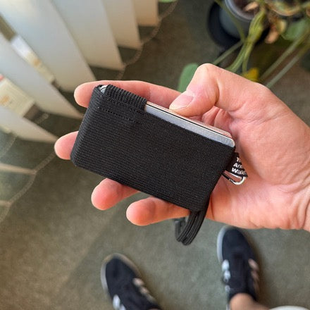 A black YAW wallet held in one hand, cards showing along the top edge