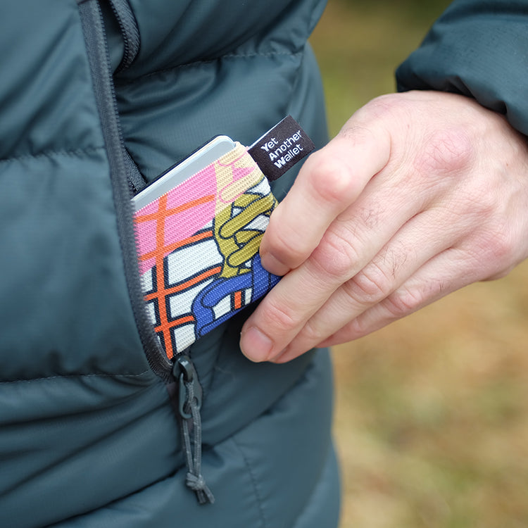 Una mano saca una cartera YAW estampada del bolsillo de una chaqueta